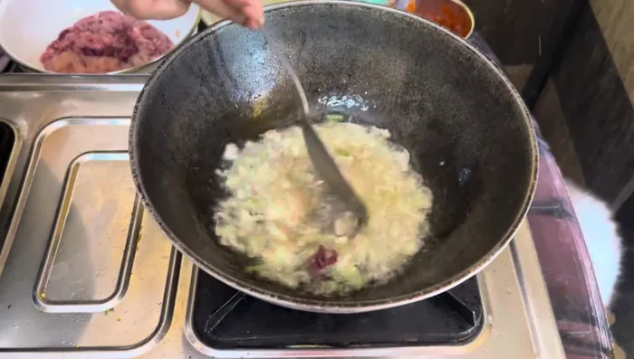 In a kadai, cut and add ginger, garlic, and onion roots.