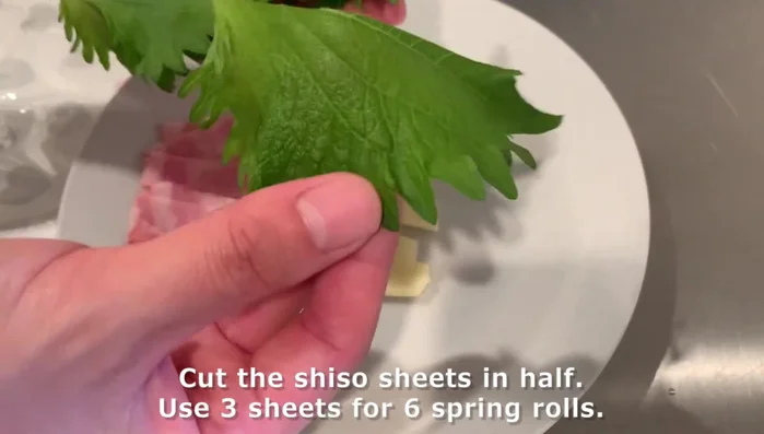 Prepare spring roll ingredients: Cut shiso sheets in half (use 3 sheets for 6 rolls), bacon, and cheese into small rectangles.