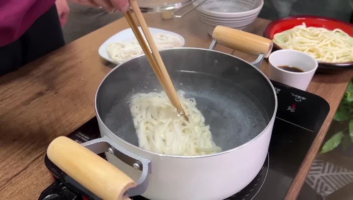 Cook frozen udon noodles in boiling water for 1 minute. Drain and rinse with cold water.