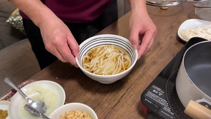 Serve noodles in a bowl, pour soup over, and add toppings like tenkasu, green onions, kamaboko, and grated ginger.