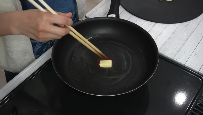 Melt the butter in a frying pan over medium heat. Add the garlic and cook until fragrant, then add the onions.