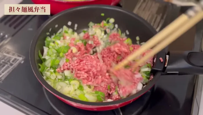 In a separate pan, add 1 tablespoon sesame oil, spring onions, and minced meat; stir-fry until meat changes color.