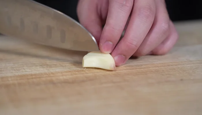 Finely mince one clove of garlic by making vertical and horizontal cuts before chopping.