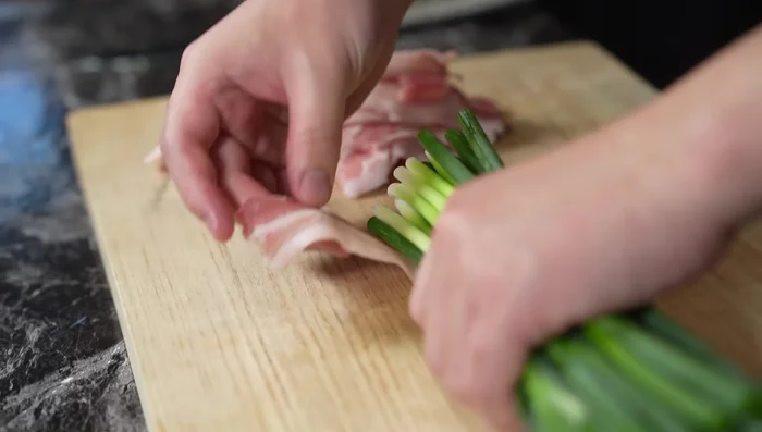 Flatten the pork belly slices and wrap them around the chives, slightly overlapping the slices to prevent them from coming apart.