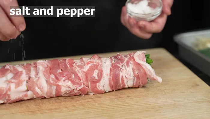 Season the wrapped pork with salt and pepper, rotating the rolls to ensure even coating.