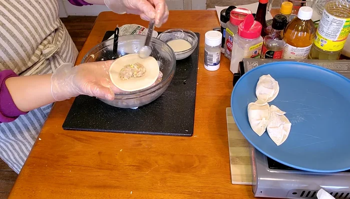 Place a gyoza wrapper on a flat surface. Add a spoonful of the filling to the center.