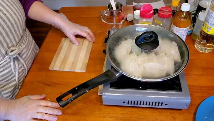 Cook for about 3 minutes, until the bottoms are lightly browned. Then, add 1/3 cup of water, cover the pan, and reduce heat to low. Steam for 5-10 minutes, or until the water is absorbed and the gyoza are cooked through.