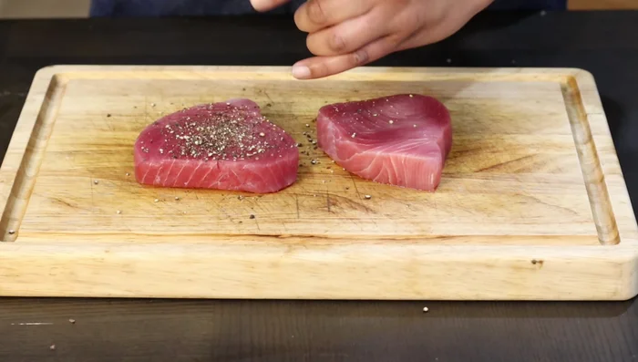 Season tuna steaks with black pepper. Sear both sides in a hot pan with avocado oil. Drizzle the tuna sauce over the steaks during cooking to fully coat all sides. (277.199)
