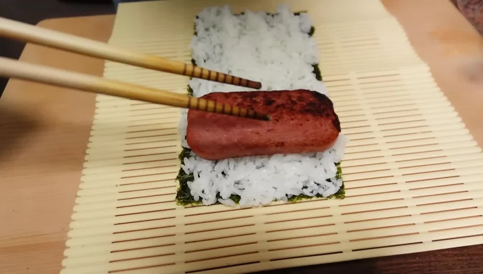 Basic Pama: Arrange spam and omelette slices on the rice. Fold the nori in half to enclose the filling.
