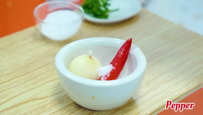 Prepare Sriracha sauce: mash chilies, garlic, sugar, pepper, and lemon.