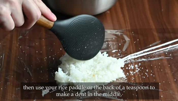 Alternatively, use plastic wrap: Sprinkle salt on the wrap, place rice in the center, make a dent, add filling, and pull opposite edges to close, shaping as usual. Add nori before serving if not freezing.