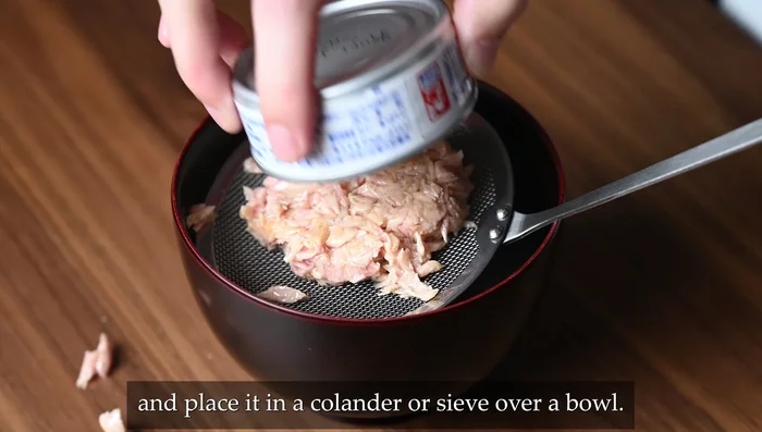 Drain canned tuna in a colander over a bowl, squeezing out excess liquid thoroughly.