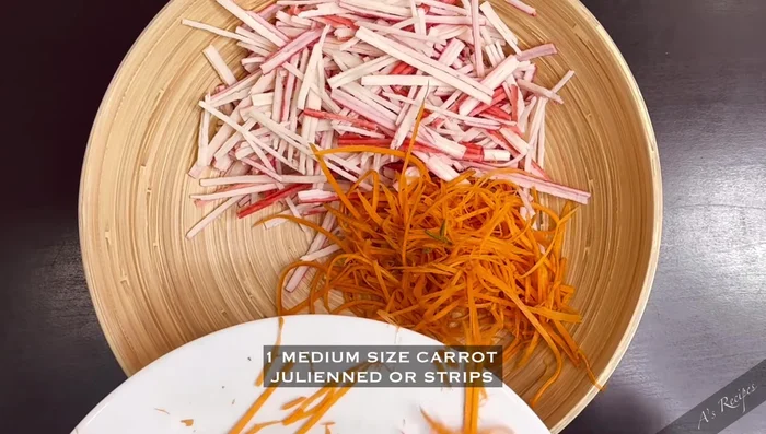 Add julienned carrot, julienned cucumber, and sliced mango to the bowl with the crab sticks.
