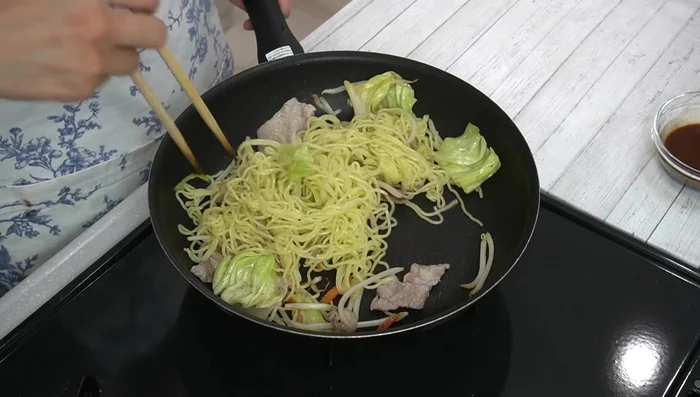 Add noodles and sauce: Add the softened noodles to the pan, loosen them, and pour in the prepared yakisoba sauce. Stir-fry until moisture evaporates.