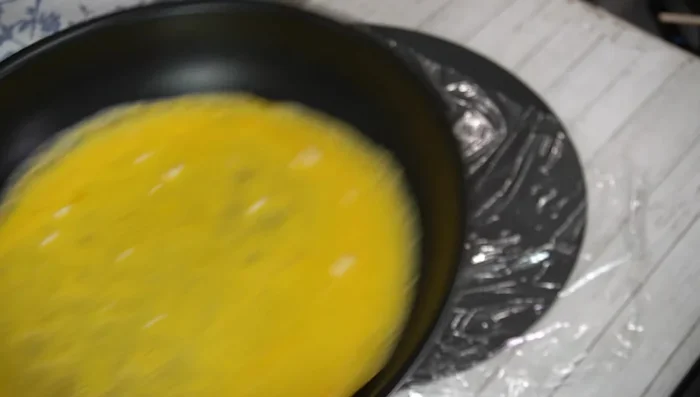 Assemble the Omu-Soba: Place a sheet of plastic wrap on a cutting board. Carefully remove the omelet and place half onto the plastic wrap. Add the yakisoba on top, then fold the omelet over. Invert onto a plate.