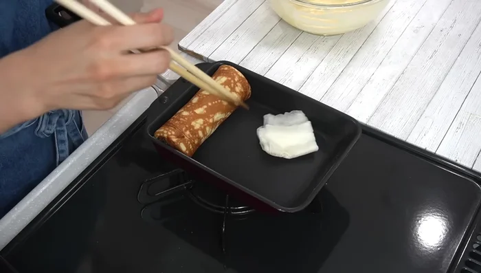 Repeat steps 11 and 12 until all batter is used, adjusting heat as needed to avoid burning. Roll the Baumkuchen when the surface bubbles and before it dries completely. Brush with oil after each roll.