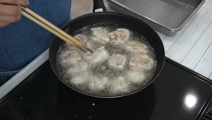 Flip the chicken and continue frying without moving until the batter is firm. Remove any excess batter that falls into the oil.