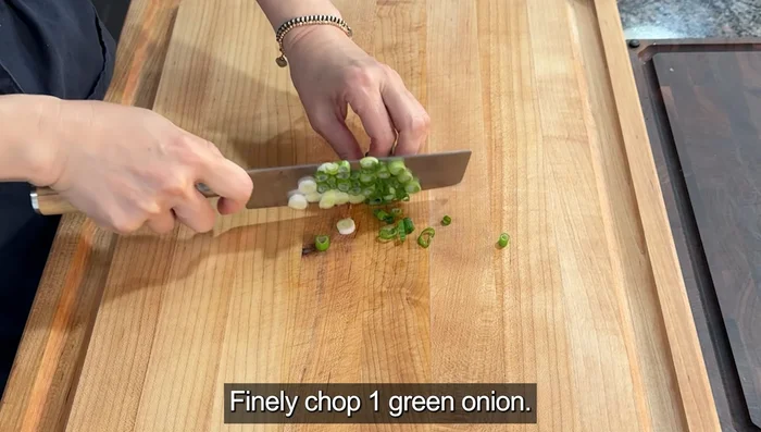 Finely chop one green onion and slice a boiled egg in half for topping.