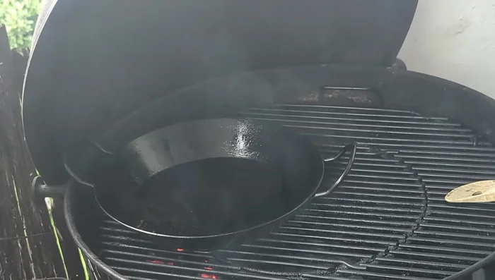 Prepare the grill with a direct and indirect zone. Place an iron pan in the indirect zone to warm up.