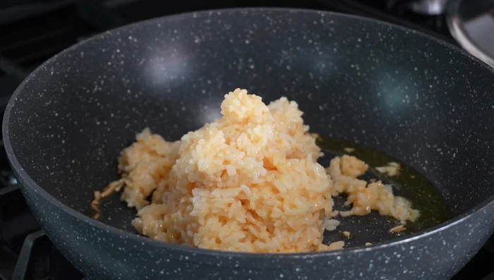 Add rice and egg mixture to the pan. Stir-fry quickly over high heat. Sprinkle in Chinese soup stock powder.