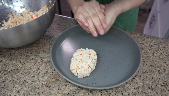 In a large bowl, combine cooled tofu, onion, carrot, salt, egg, bread crumbs, grated ginger, and pepper. Mix thoroughly until sticky.