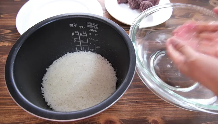 Take a portion of the cooked glutinous rice (approximately 50g), gently flatten it in your hand, and place a portion of red bean paste in the center.