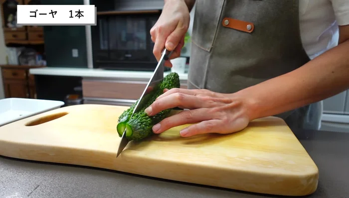Remove both ends of the goya and cut it in half.