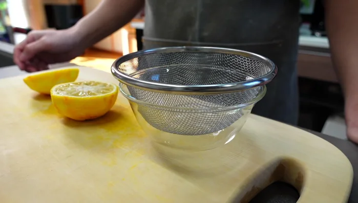 Using a strainer, gently squeeze the juice from the yuzu by hand. Avoid squeezing too hard, as it can make the juice bitter.