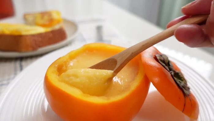 Prepare persimmon pudding. (Note: Detailed instructions for pudding preparation are not given, but it mentions using the persimmons' characteristic of solidifying when mixed with calcium.)
