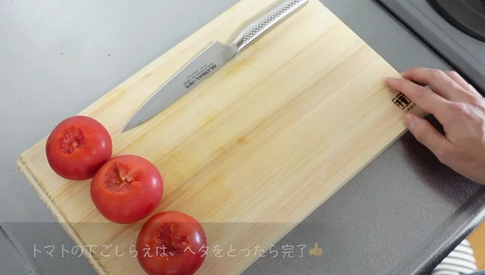 Prepare the tomatoes for a second dish: take the stems off of three tomatoes.