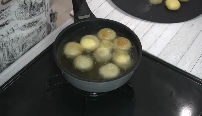 Carefully place the dough balls in the hot oil, leaving some space between them. Fry for approximately 4 minutes, rolling the donuts occasionally to ensure even browning.