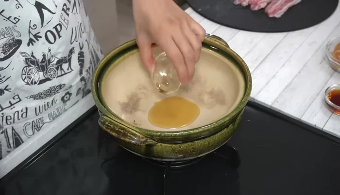 Heat sesame oil in a clay pot over medium heat. Add garlic and cook until fragrant.