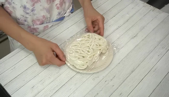 Microwave frozen udon noodles, covered with plastic wrap, at 600W for 2 minutes to defrost partially.