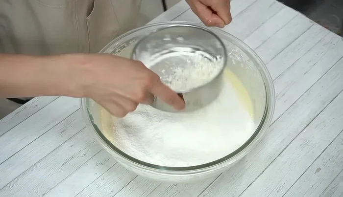 Gently fold in the flour using a rubber spatula. Then, gradually incorporate the melted butter and milk mixture, ensuring not to overmix.