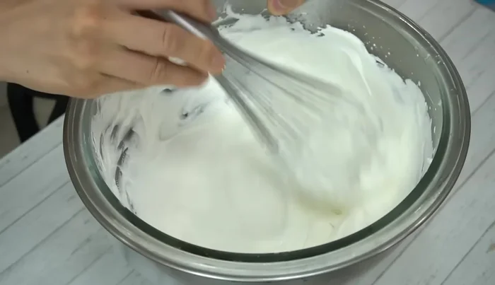 Apply a thin layer of the remaining soft cream to the entire cake as a primer, then add a final layer of cream and smooth it with a palette knife. Create a textured look by gently scratching the cream.
