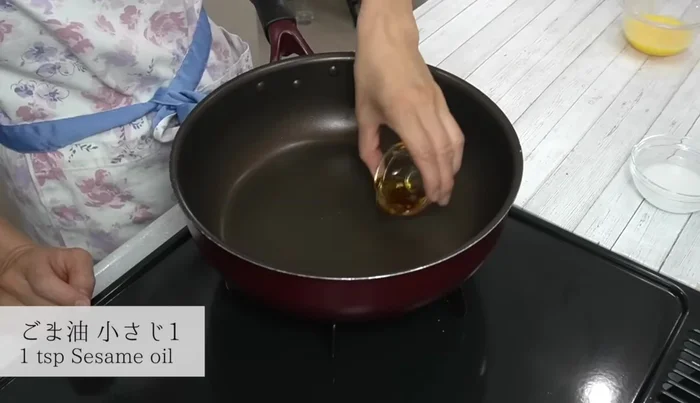 Heat sesame oil in a frying pan over medium heat. Add Chinese cabbage, garlic, and sake. Stir-fry lightly.
