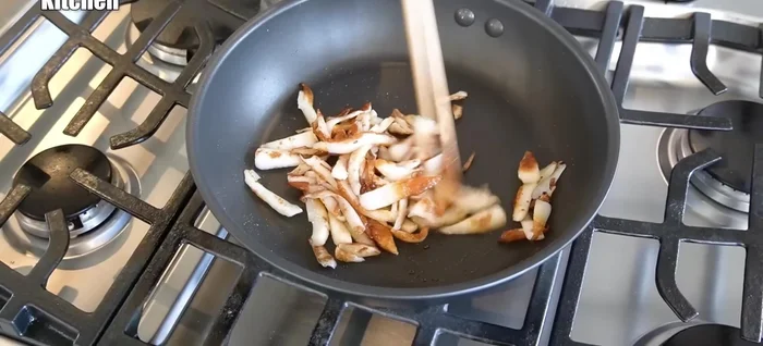 Season the chikuwa with grated garlic and sesame oil. Add the green onions and stir-fry until well combined.