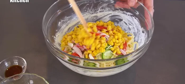 Add the prepared onions, cucumbers, crab sticks, and corn. Mix thoroughly.