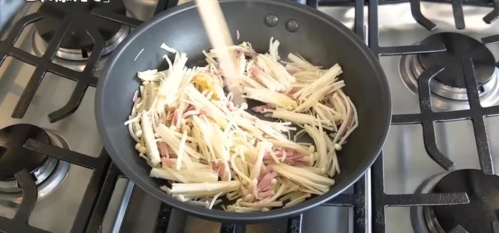 Add the enoki mushrooms and bacon to the pan and fry until the enoki mushrooms are slightly softened and the bacon is cooked.