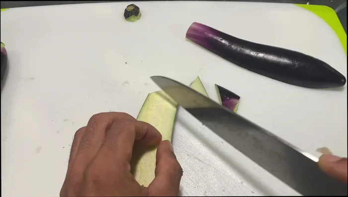 Cut the eggplant in half, remove the top piece, and then cut into diagonal pieces.