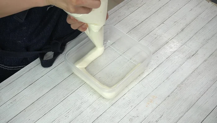 Layer 1/3 of the tiramisu batter in the Tupperware.