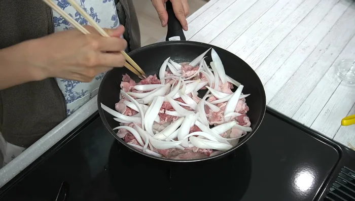 Add the sliced onions to the pan and continue cooking until the onions are softened and the pork is cooked through.