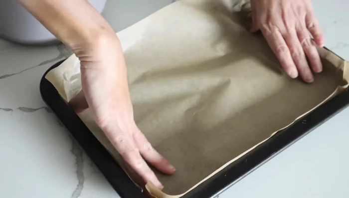 Line a baking sheet with parchment paper and spread the granola mixture.