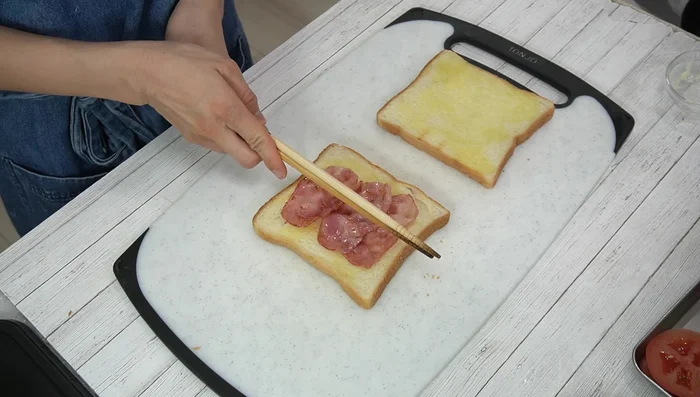 Assemble sandwich: spread sauce, layer bacon, fried egg, tomato, and lettuce.