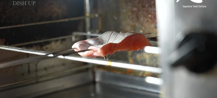 Slowly grill the skewered salmon, flipping once it starts to brown. Avoid high heat to prevent burning.