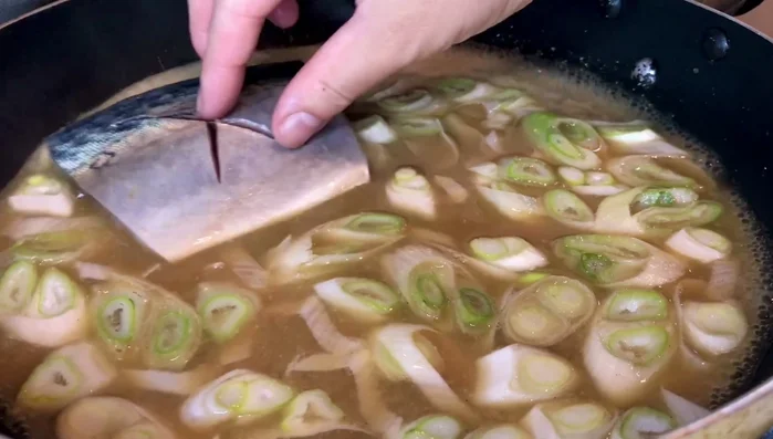 Once boiling, add the mackerel fillets in a single layer, skin side up. (115.619)