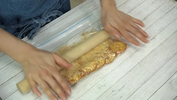 Assemble the cracker base: Press the mixture into the bottom of the prepared cake mold, ensuring it's tightly packed.