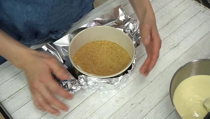 Bake the cheesecake: Pour the batter into the prepared mold. Cover the bottom of the mold with aluminum foil. Place the mold in a heat-resistant tray and surround it with hot water (80°C). Bake in a preheated oven at 160°C for 50 minutes, covering with aluminum foil if it starts to brown too much.