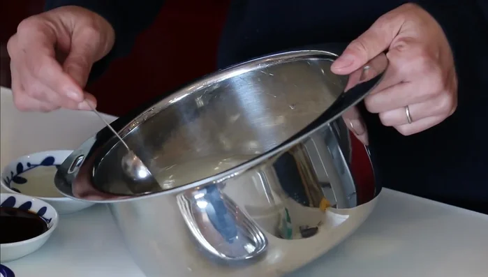 Remove 4 tbsp of water from the soaked rice. Add hondashi, soy sauce, and sake to the rice.