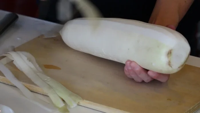 Peel and cut the daikon radish into sticks using a vegetable peeler. Cut off the top and bottom ends.